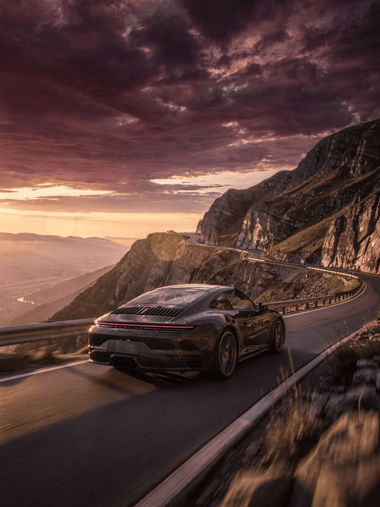 Porsche 911 sports car on scenic mountain road at sunset